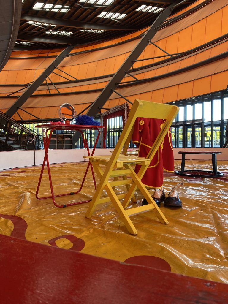 Scénette clown avec chaise jaune, perruque bleue et costume rouge pour location décor cirque