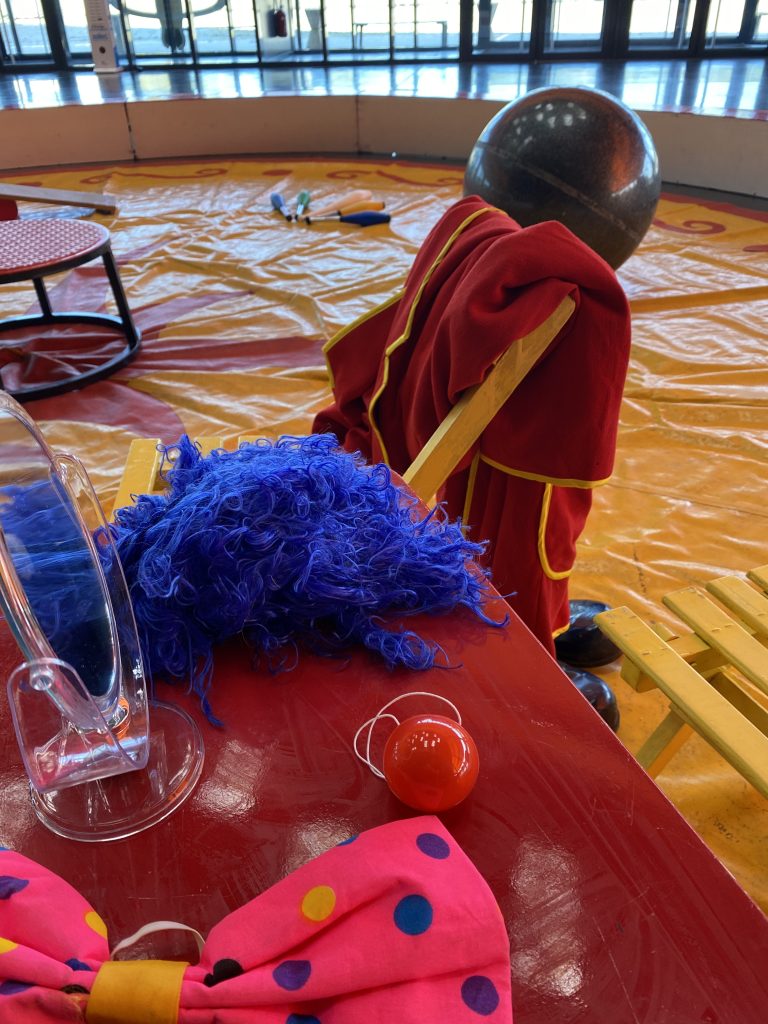 Détail scénette clown perruque bleue, nœud rose et accessoires cirque pour décoration immersive